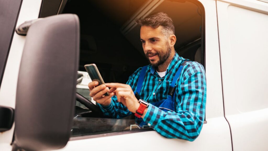 Conta digital MEI: caminhoneiro n ajanela do caminhão, mexendo em um celular